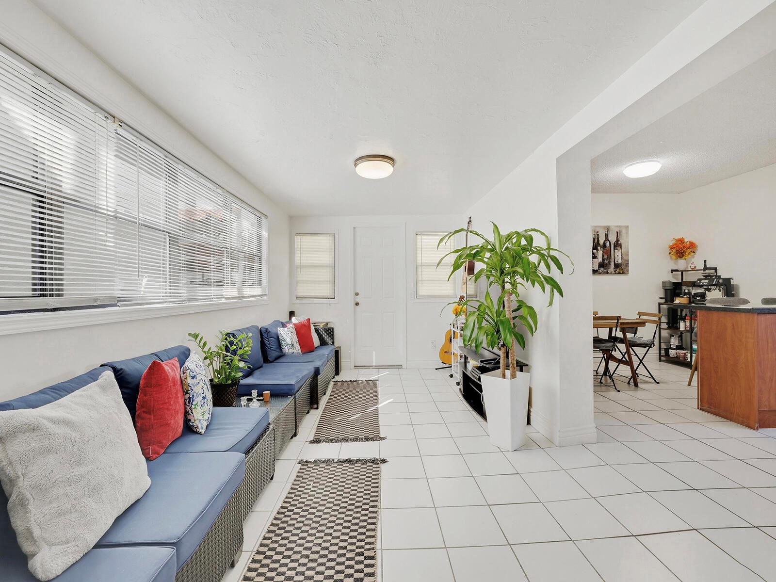 A sunroom with white tile floors, blue cushioned seating, and a large potted plant — 9702 NW 5th Lane # 9702, Miami FL 33172, MIAMI, FL