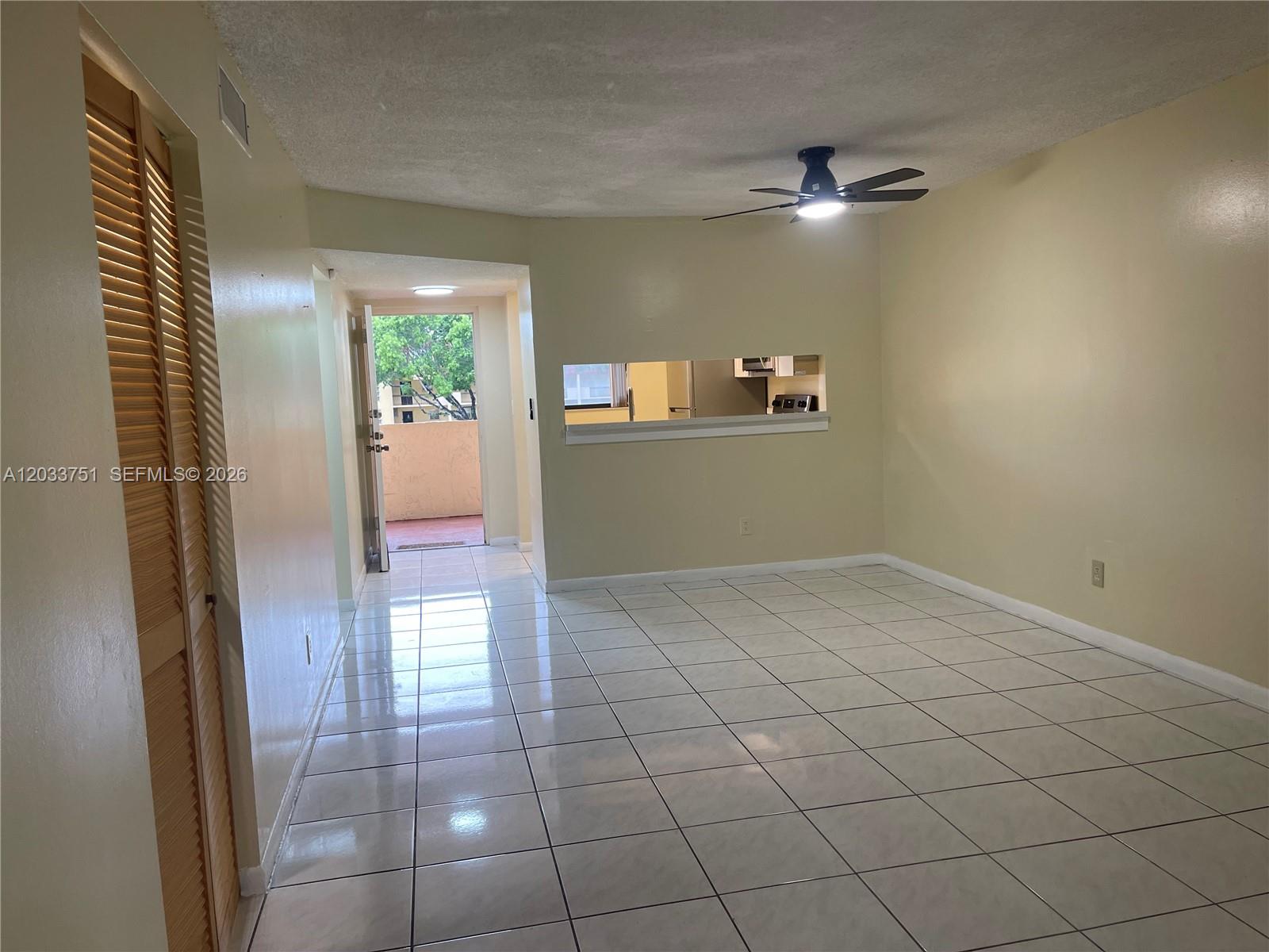 A tiled living area features a ceiling fan, a pass-through window, and an open doorway — 3252 Foxcroft Rd # 307, Miramar FL 33025, MIRAMAR, FL