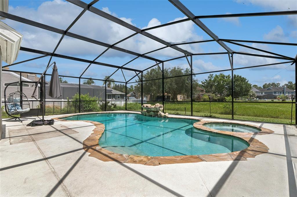 A screened-in swimming pool and hot tub with a rock waterfall feature on a patio — 2743 RUNNING SPRINGS LOOP, OVIEDO, FL