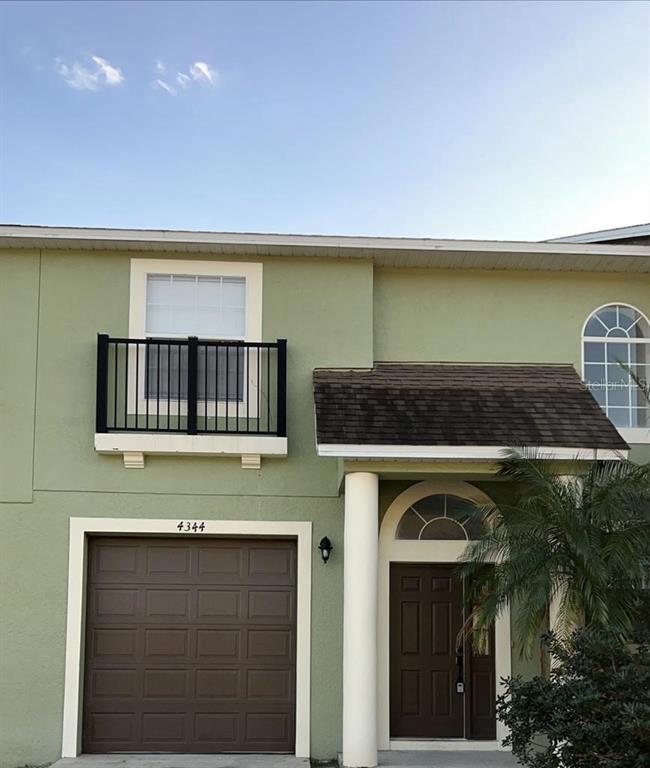 A two-story house exterior features a brown garage door, a balcony, and a front entrance — 4344 PARADISE COVE COURT, KISSIMMEE, FL