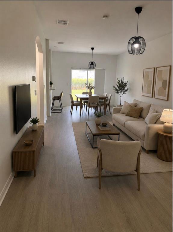 A living room and dining area with light wood flooring, neutral furniture, and pendant lighting — 4344 PARADISE COVE COURT, KISSIMMEE, FL