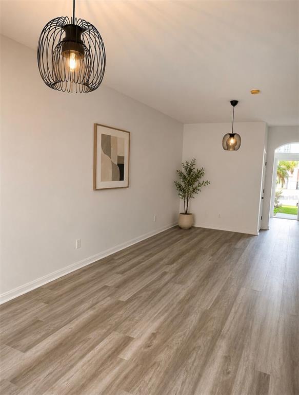 An empty room features light wood-look flooring, two pendant lights, and a potted plant — 4344 PARADISE COVE COURT, KISSIMMEE, FL
