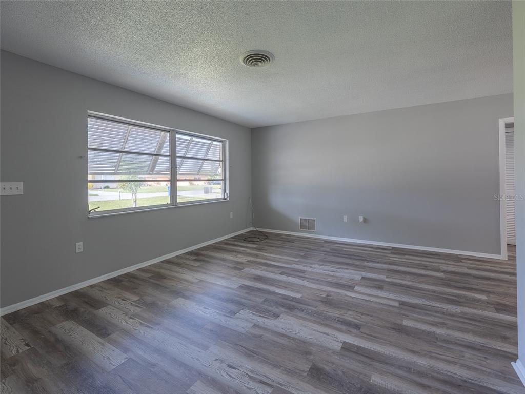 An empty room with gray walls, wood-look flooring, and a ceiling air vent — 916 GILLESPIE STREET, ENGLEWOOD, FL