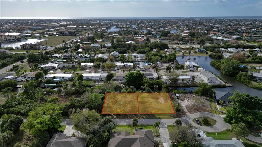 An aerial view shows two adjacent vacant lots outlined in orange in a residential neighborhood — 3015 BANYAN WAY, PUNTA GORDA, FL