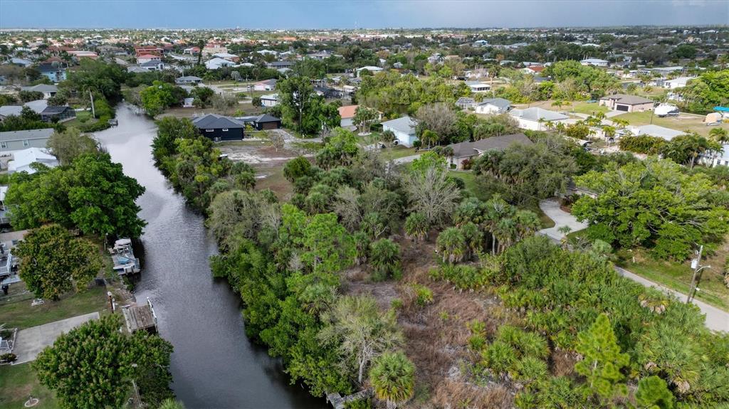 An aerial view shows a narrow canal winding through a residential neighborhood with lush vegetation — 3015 BANYAN WAY, PUNTA GORDA, FL