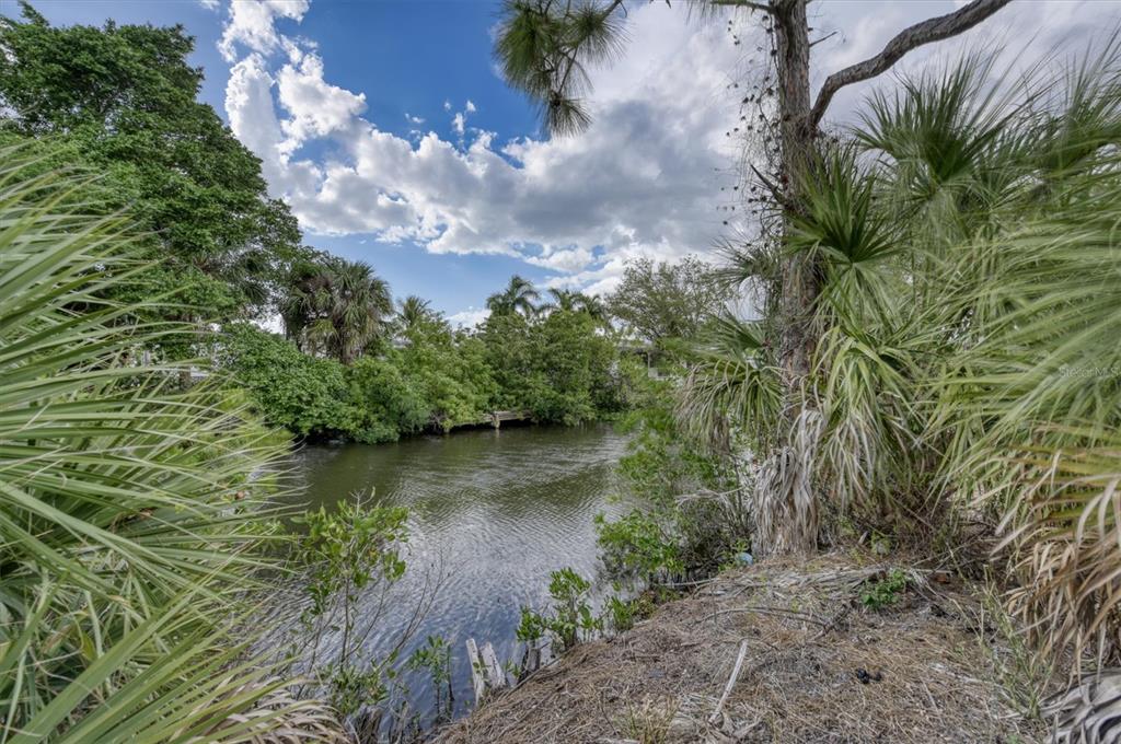 A view of a narrow canal surrounded by lush green trees and palm trees — 3015 BANYAN WAY, PUNTA GORDA, FL
