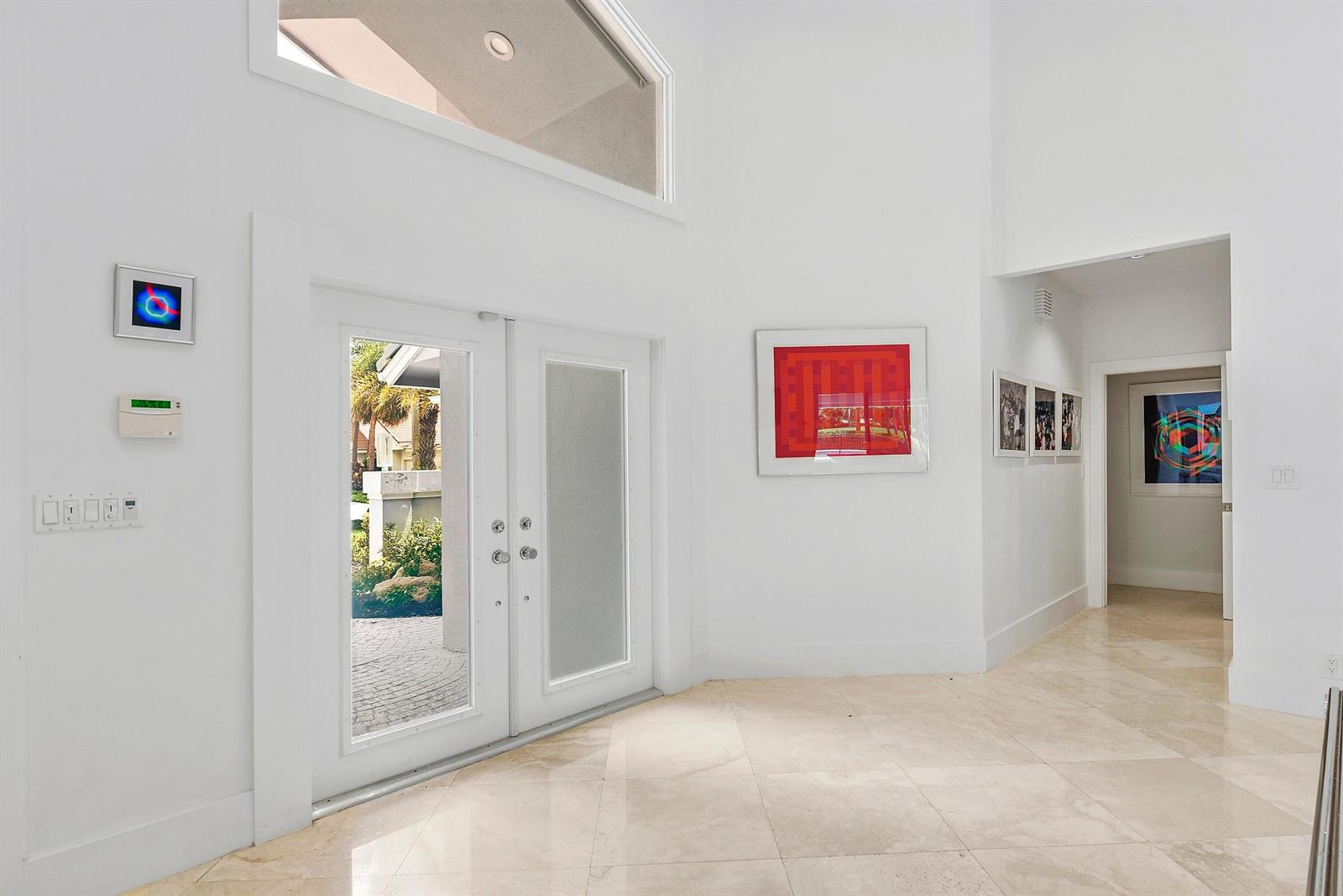 A bright entryway features white walls, marble flooring, double glass doors, and modern art pieces — 17771 Foxborough Lane, Boca Raton FL 33496, BOCA RATON, FL