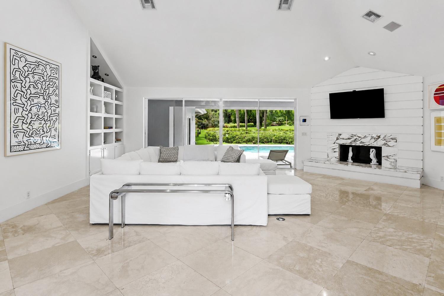 A bright living room features a white sectional sofa, fireplace, and sliding doors to a pool — 17771 Foxborough Lane, Boca Raton FL 33496, BOCA RATON, FL