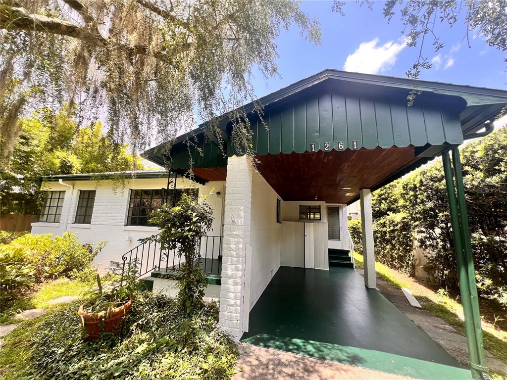 A white brick house features a green-trimmed carport and a small front porch — 1261 RICHMOND ROAD, WINTER PARK, FL