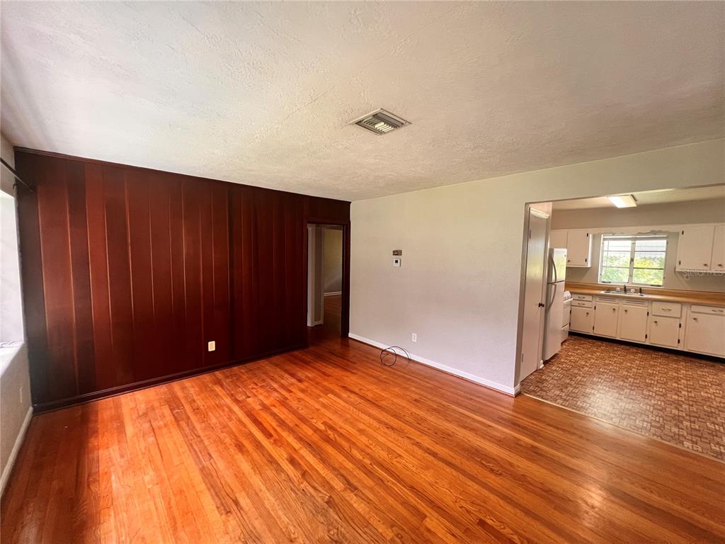 A living room with wood paneling and hardwood floors opens into a kitchen with cabinets — 1261 RICHMOND ROAD, WINTER PARK, FL