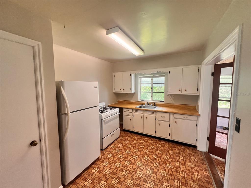 A kitchen features white cabinets, a white refrigerator, a gas stove, and patterned tile flooring — 1261 RICHMOND ROAD, WINTER PARK, FL