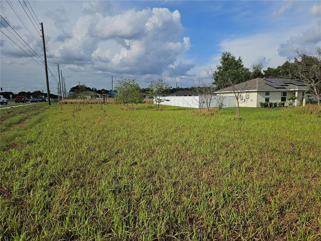 A vacant grassy lot sits next to a single-story house with a white privacy fence — 0 DOGWOOD DR CIRCLE, OCALA, FL
