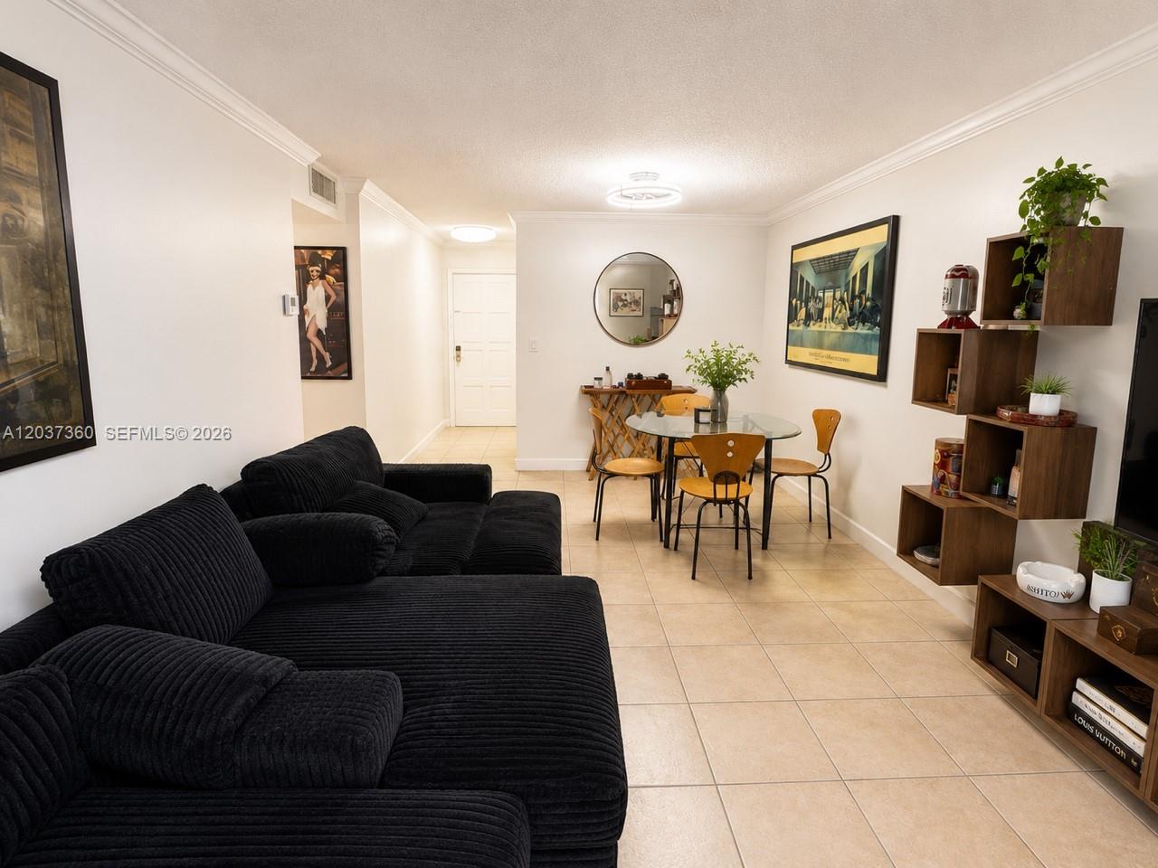 A living and dining area features a black sectional sofa, glass table, and wooden shelving — 8650 SW 109th Ave # 103, Miami FL 33173, MIAMI, FL