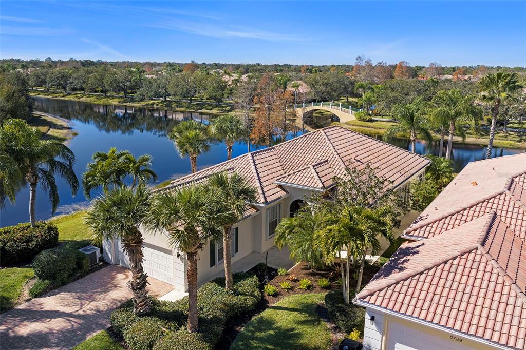 An aerial view shows a house with a tiled roof next to a lake and bridge — 5735 WILENA PLACE, SARASOTA, FL