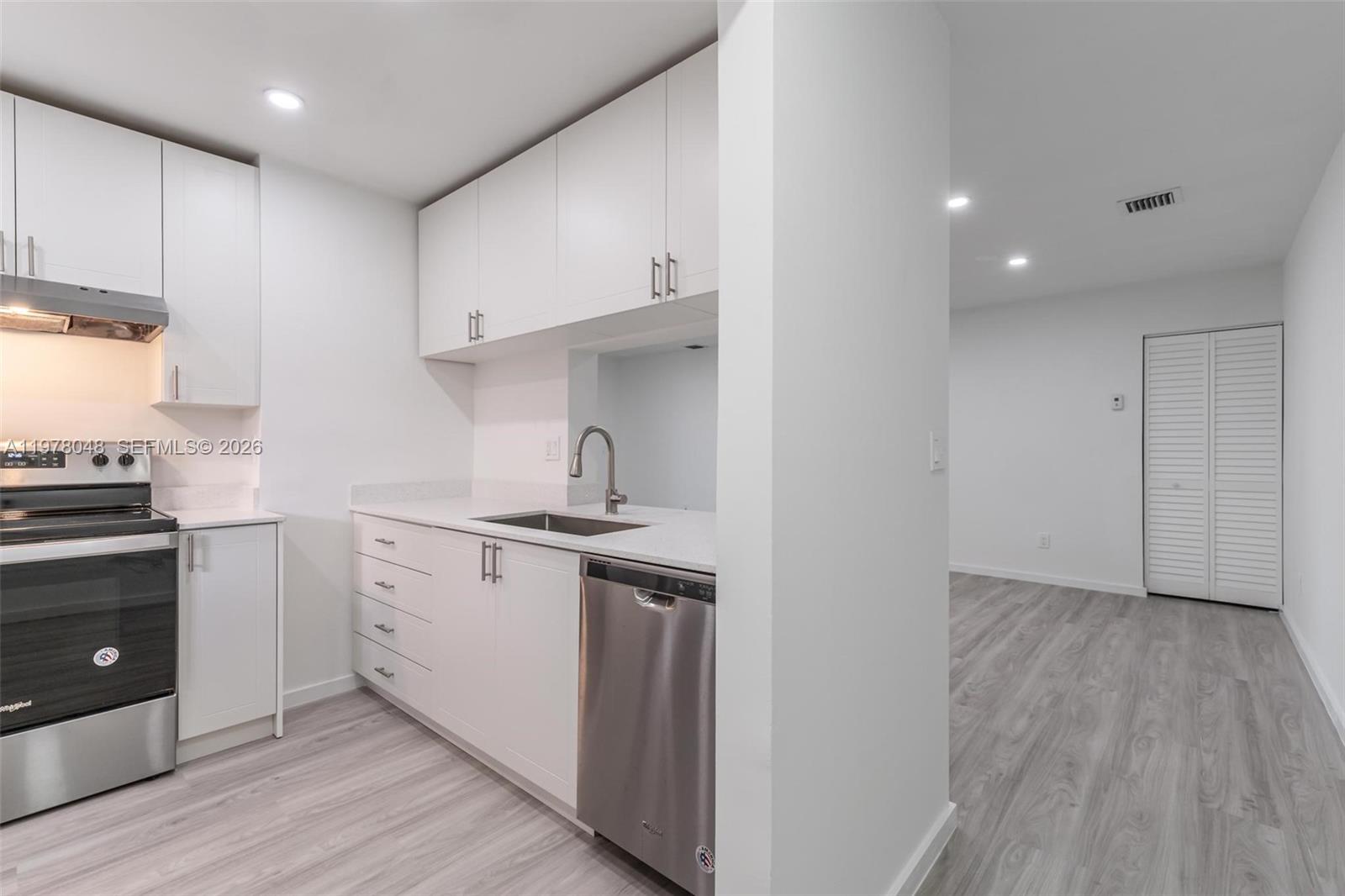 A modern kitchen features white cabinets, stainless steel appliances, and light wood-look flooring — 3631 NW 94th Ave # 6G, Sunrise FL 33351, SUNRISE, FL
