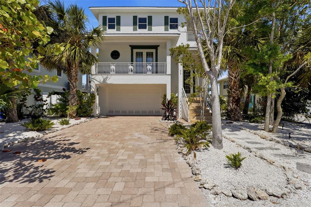 A three-story white house with a paved driveway, a garage, and a second-floor balcony — 418 PINE AVENUE, ANNA MARIA, FL