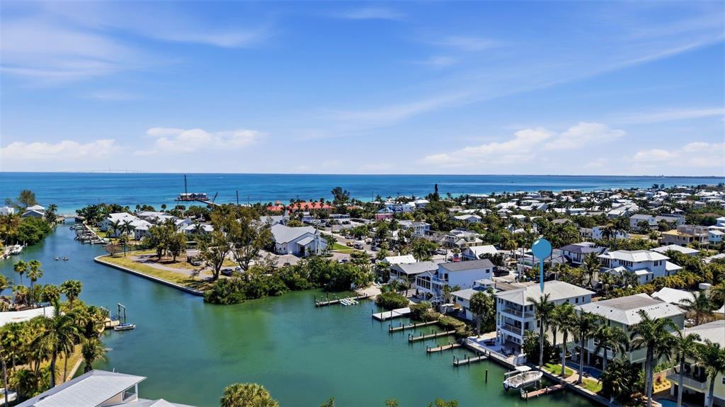 An aerial view shows a coastal neighborhood with houses along a canal and the ocean — 418 PINE AVENUE, ANNA MARIA, FL