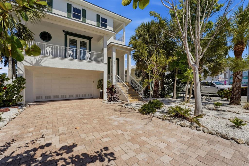 A white three-story house with a paved driveway, a garage, and a second-floor balcony — 418 PINE AVENUE, ANNA MARIA, FL