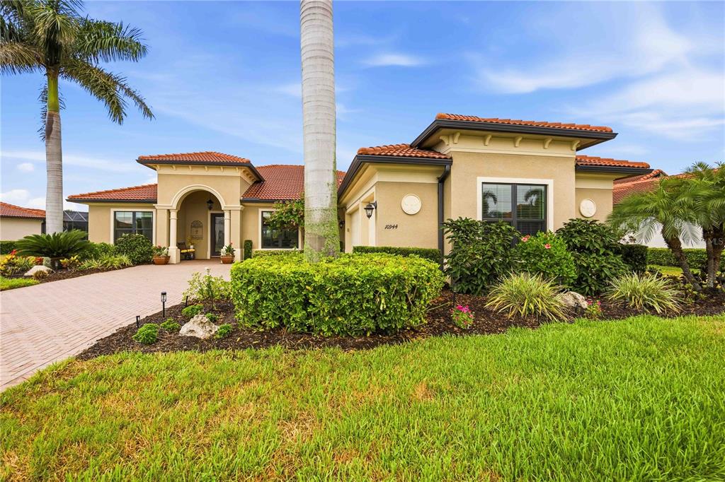 A single-story house with a tile roof, beige stucco exterior, and a paved driveway — 10944 BULLRUSH DRIVE, VENICE, FL