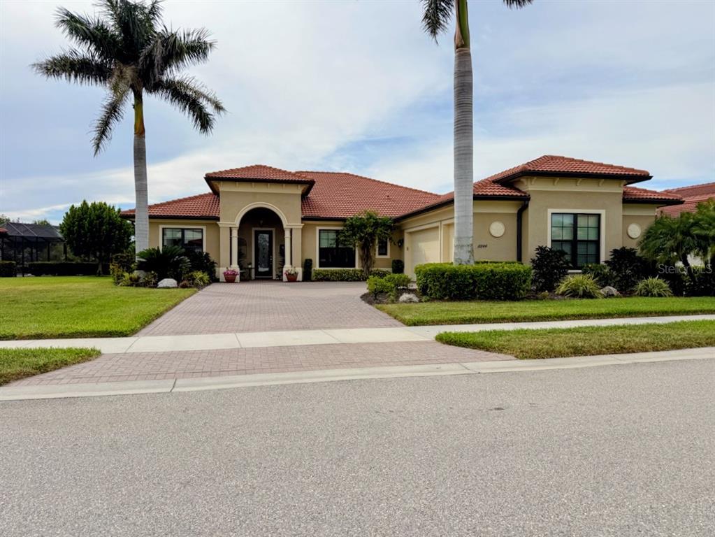 A single-story house with a tile roof, arched entryway, and palm trees in the front yard — 10944 BULLRUSH DRIVE, VENICE, FL