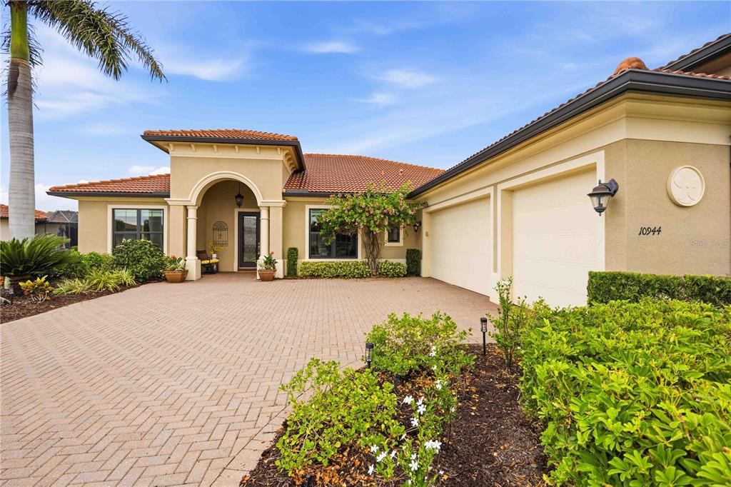 A single-story house with a beige stucco exterior, tile roof, and a paved driveway — 10944 BULLRUSH DRIVE, VENICE, FL