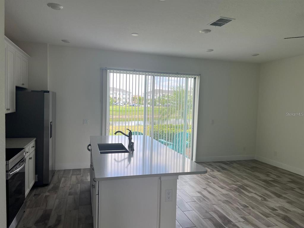 A kitchen with a central island, stainless steel appliances, and a sliding glass door view — 3077 CARIBBEAN SOUL DRIVE, KISSIMMEE, FL