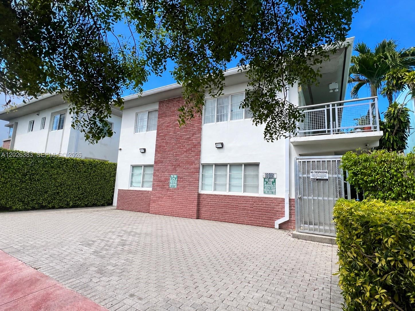 A two-story building with a brick facade and a paved driveway stands under trees — 6905 Bay Dr # 13, Miami Beach FL 33141, MIAMI BEACH, FL