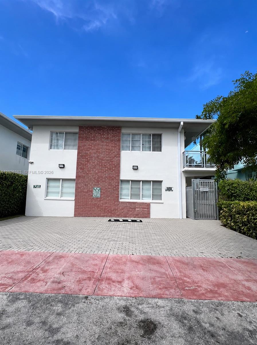 A two-story building features a central red brick facade and a paved parking area — 6905 Bay Dr # 13, Miami Beach FL 33141, MIAMI BEACH, FL