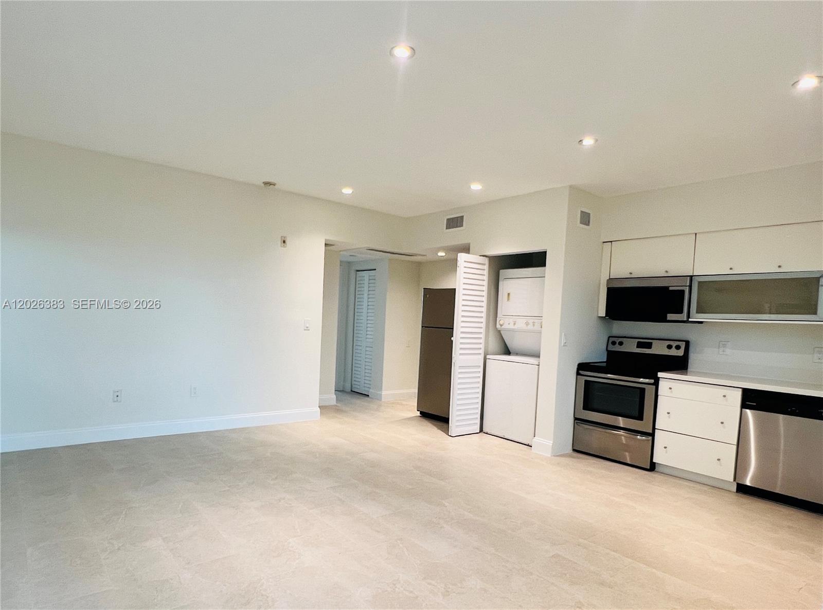 A kitchen area features white cabinets, stainless steel appliances, and a stacked laundry unit — 6905 Bay Dr # 13, Miami Beach FL 33141, MIAMI BEACH, FL