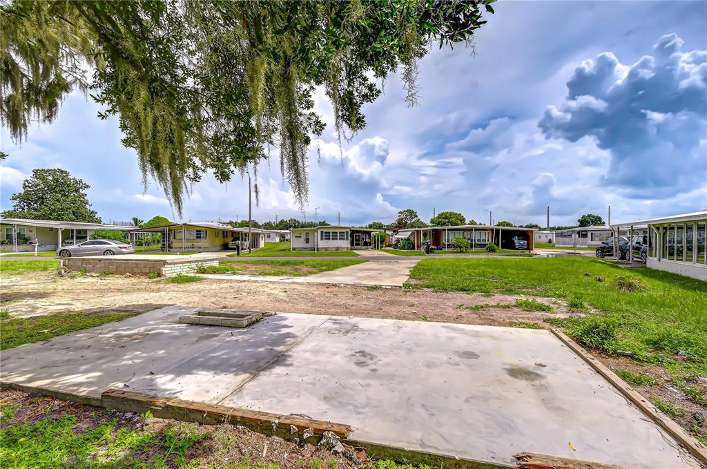 A vacant concrete pad sits in a mobile home park under a large oak tree — 35127 ZEPHYR SHORES DRIVE, ZEPHYRHILLS, FL
