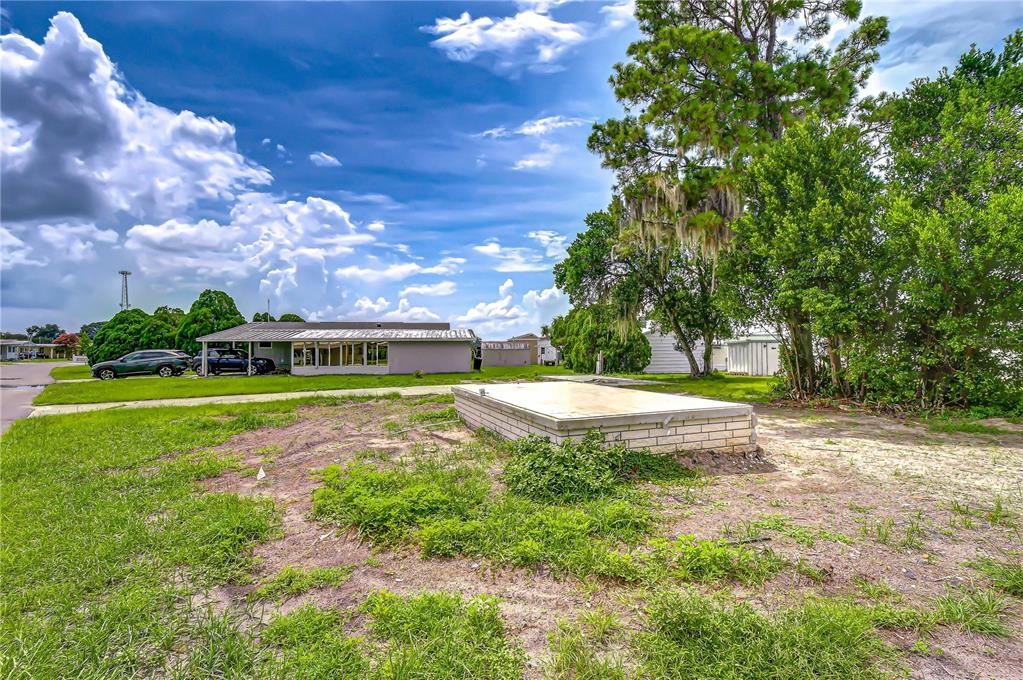 A vacant lot features a raised concrete foundation slab surrounded by grass and mature trees — 35127 ZEPHYR SHORES DRIVE, ZEPHYRHILLS, FL