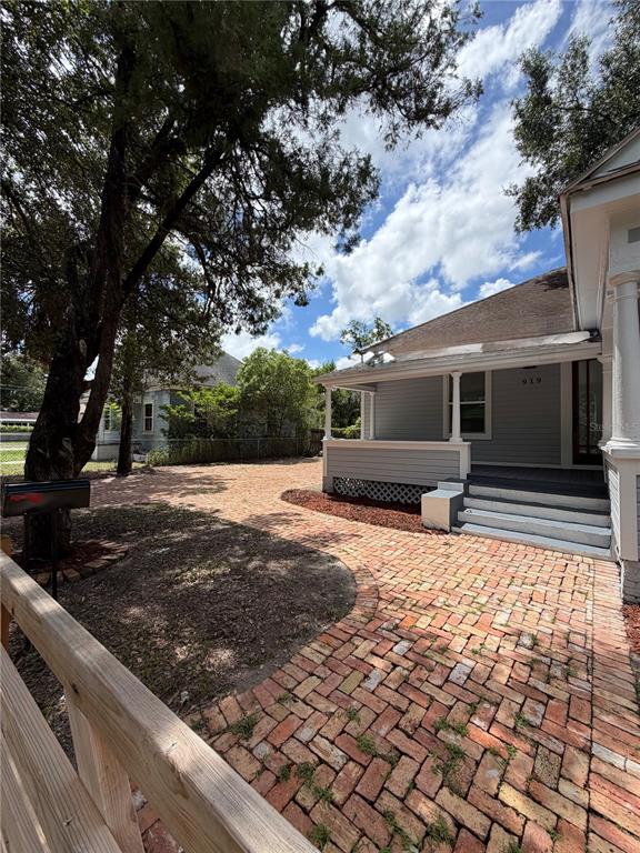 A brick-paved walkway leads to the front porch of a light gray house — 919 E 26TH AVENUE, TAMPA, FL