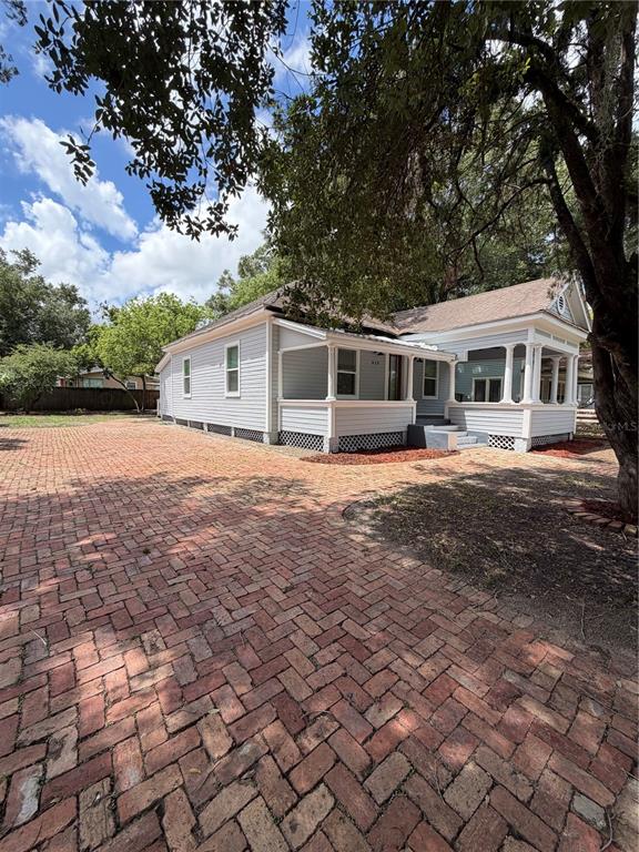 A light blue, single-story house with a brick driveway and a covered front porch — 919 E 26TH AVENUE, TAMPA, FL
