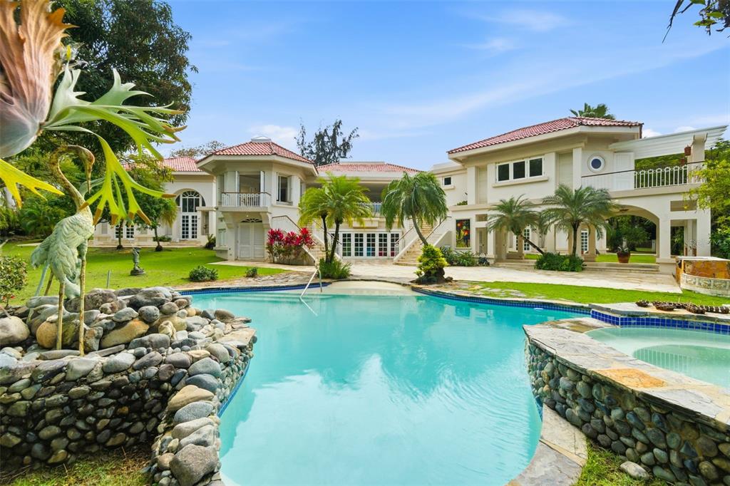 A large multi-story house with a tiled roof overlooks a swimming pool and stone spa — 15 DORADO BEACH ESTATES, DORADO, PR