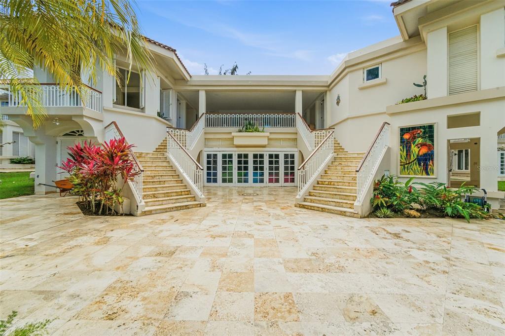 A large house exterior features a stone patio, two symmetrical staircases, and a balcony — 15 DORADO BEACH ESTATES, DORADO, PR