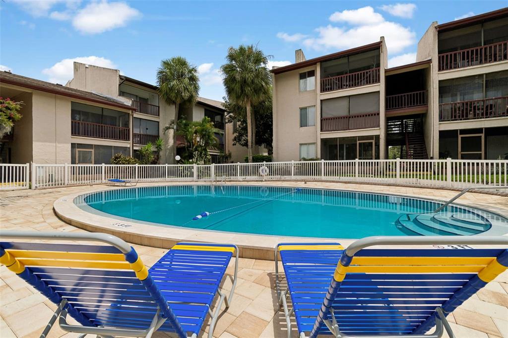 A swimming pool sits in front of a multi-story apartment building with screened balconies — 3841 S LAKE DRIVE UNIT 197, TAMPA, FL