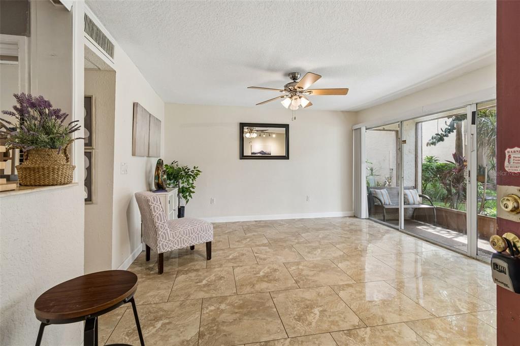 A living room with beige tile flooring, a ceiling fan, and sliding glass doors to a patio — 3841 S LAKE DRIVE UNIT 197, TAMPA, FL