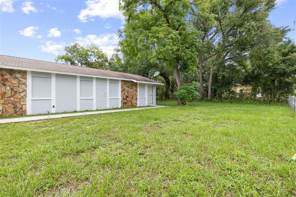 A side view of a house with stone accents, gray siding, and a grassy yard — 3713 N 34TH STREET, TAMPA, FL