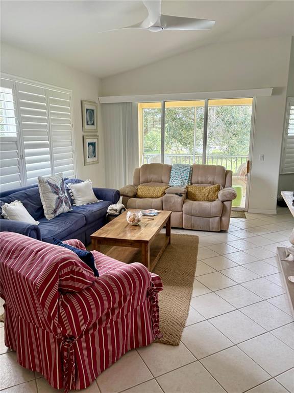 A living room features a blue sofa, a striped armchair, and a tan reclining loveseat — 703 CASA DEL LAGO WAY UNIT 703, VENICE, FL