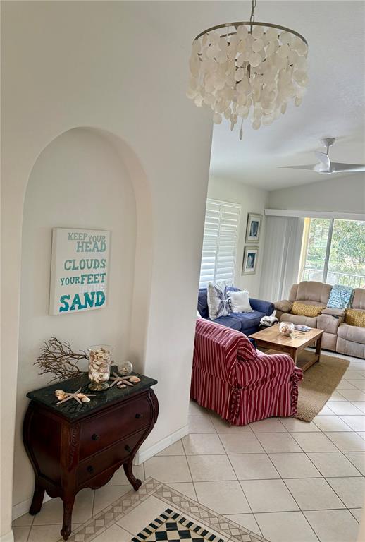 An entryway with a decorative chest leads into a living room featuring a striped chair — 703 CASA DEL LAGO WAY UNIT 703, VENICE, FL
