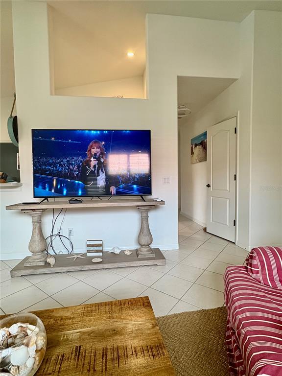 A living room features a television on a console table and a tiled floor — 703 CASA DEL LAGO WAY UNIT 703, VENICE, FL