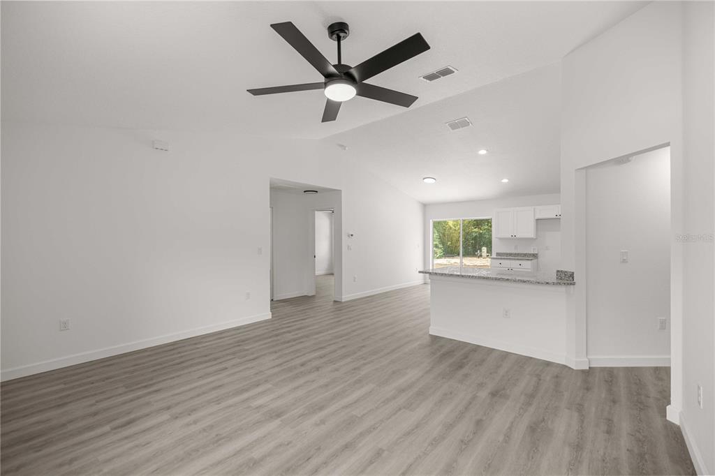 A bright, open-concept living area features light wood-look flooring, a ceiling fan, and a kitchen — 22930 SW MARINE BOULEVARD, DUNNELLON, FL