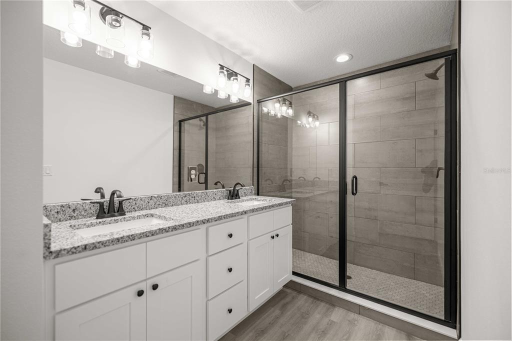 A bathroom features a double vanity with granite countertops, white cabinets, and a glass-enclosed shower — 22930 SW MARINE BOULEVARD, DUNNELLON, FL