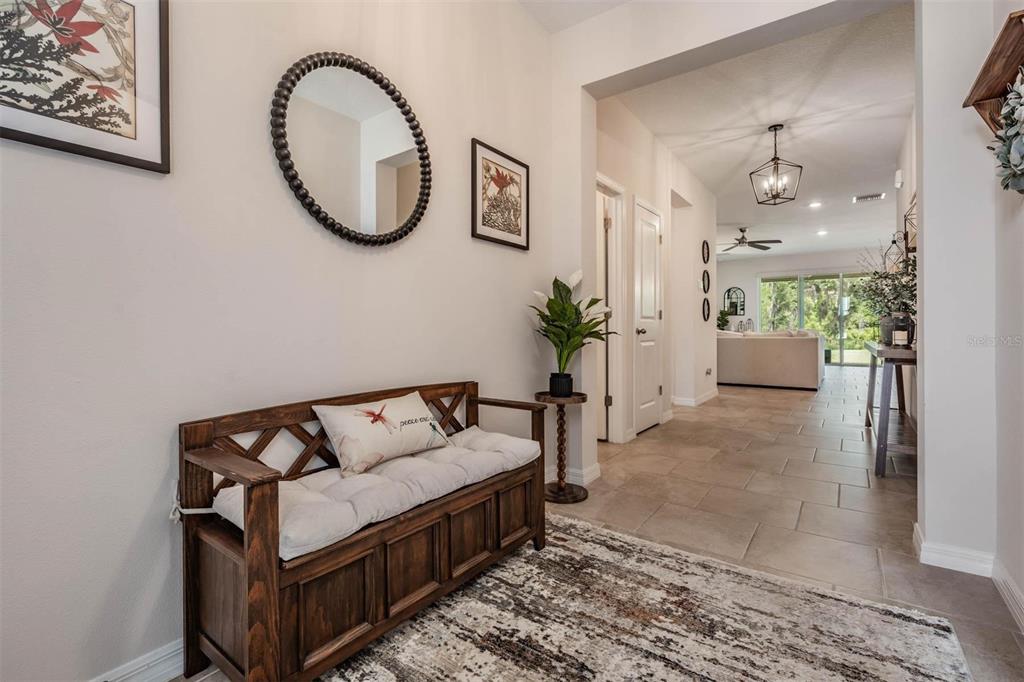 A wooden entryway bench sits on a rug in a hallway with tile flooring — 6862 BROAD RIVER AVENUE, LAND O LAKES, FL