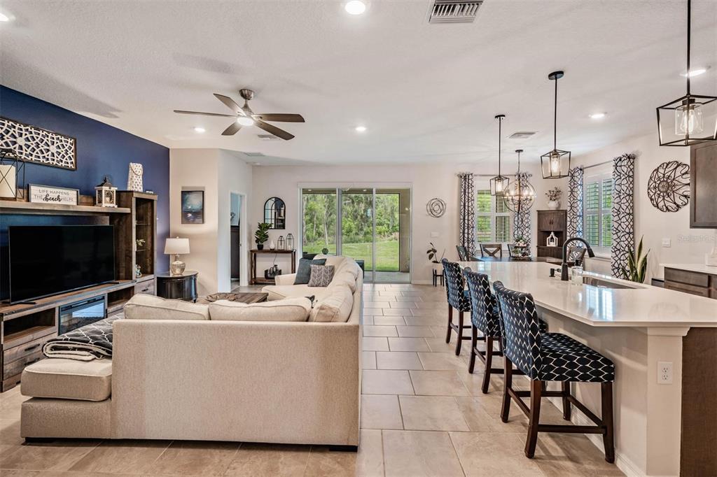 An open-concept living room and kitchen featuring a large island, tile floors, and blue accent wall — 6862 BROAD RIVER AVENUE, LAND O LAKES, FL