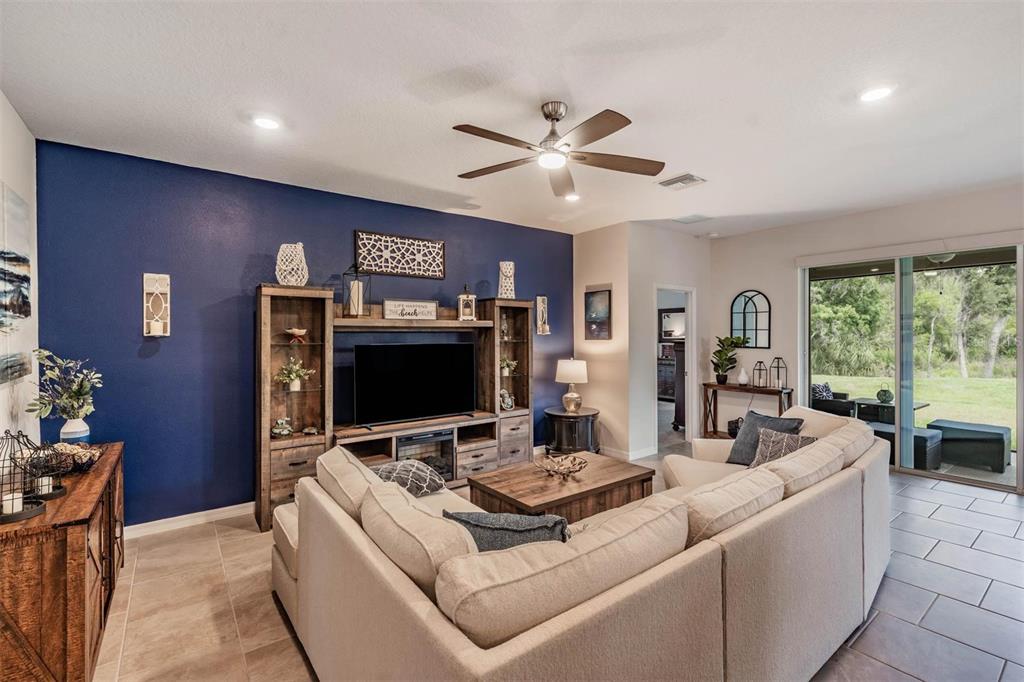 A living room features a blue accent wall, a large sectional sofa, and sliding doors — 6862 BROAD RIVER AVENUE, LAND O LAKES, FL