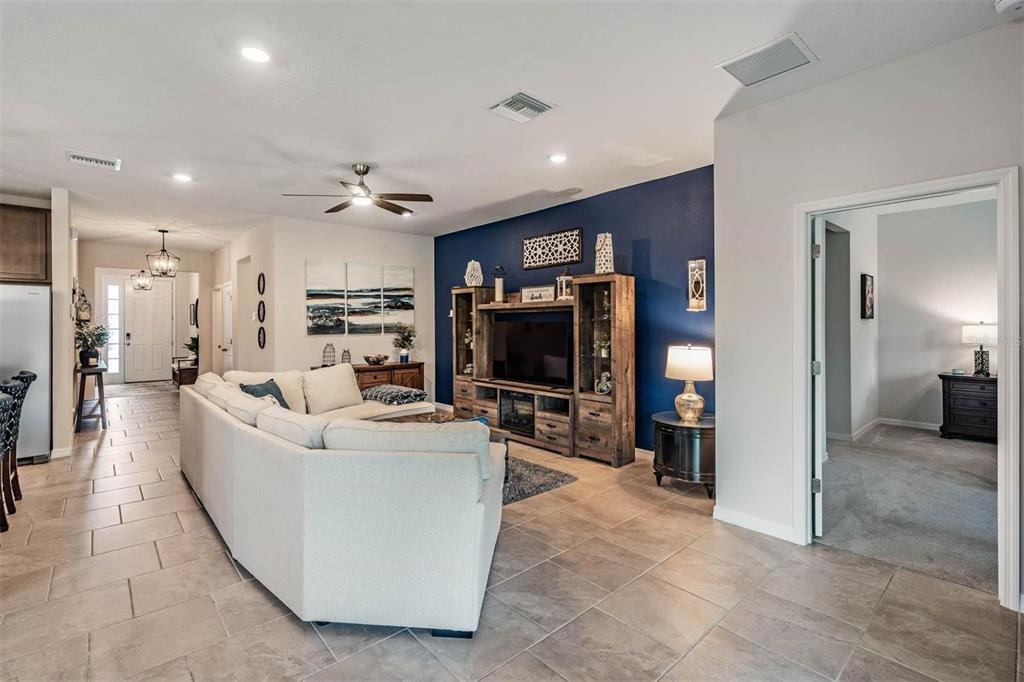 A living room features a large sectional sofa, a wooden entertainment center, and a blue wall — 6862 BROAD RIVER AVENUE, LAND O LAKES, FL