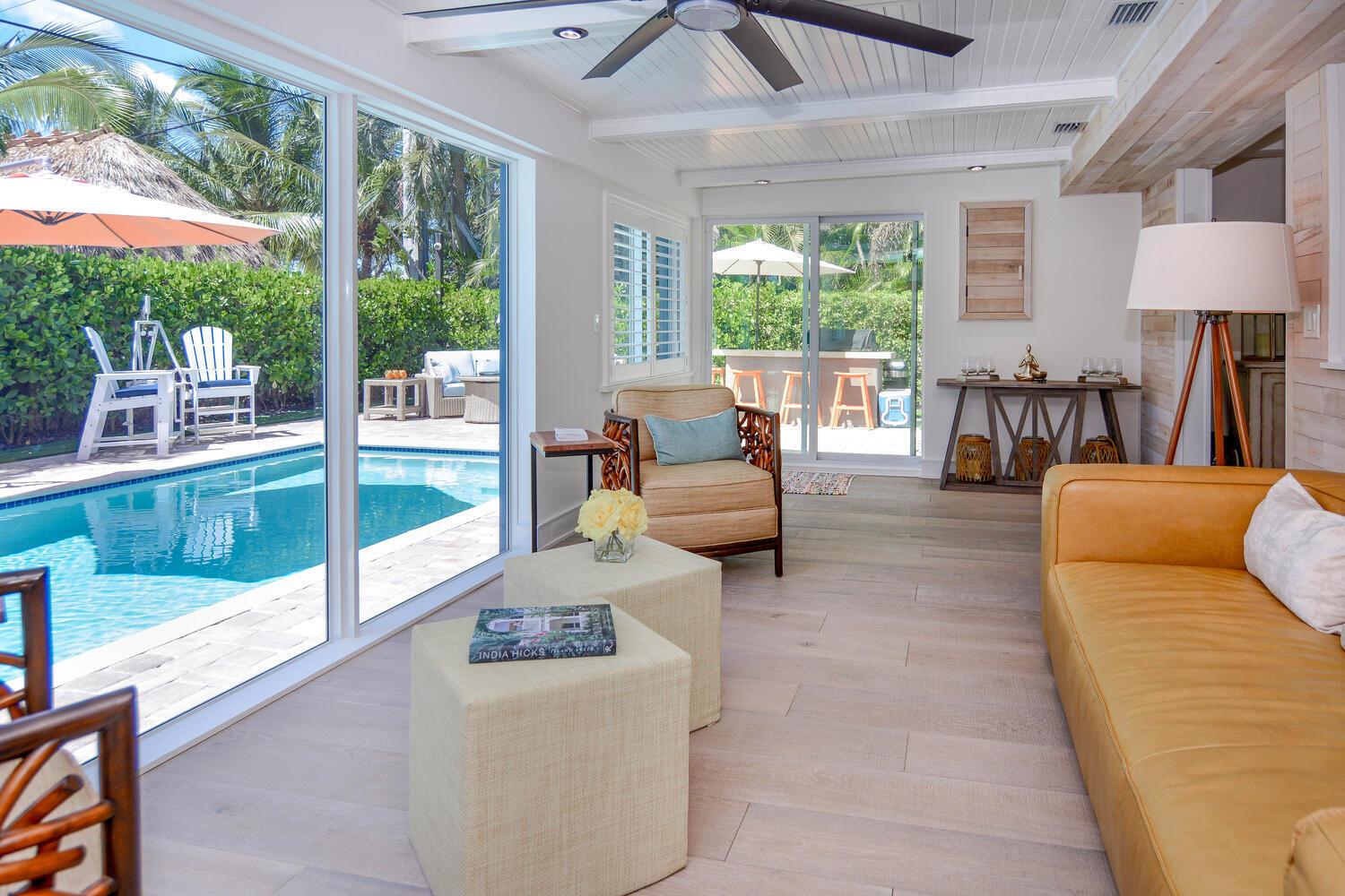 A sunroom with a tan leather sofa, two ottomans, and sliding glass doors overlooking a pool — 3396 Pebble Place, Jupiter FL 33469, JUPITER, FL