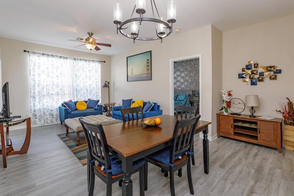 A living and dining room area features a wooden table, blue sofas, and light flooring — 2310 SILVER PALM DR UNIT 104, KISSIMMEE, FL