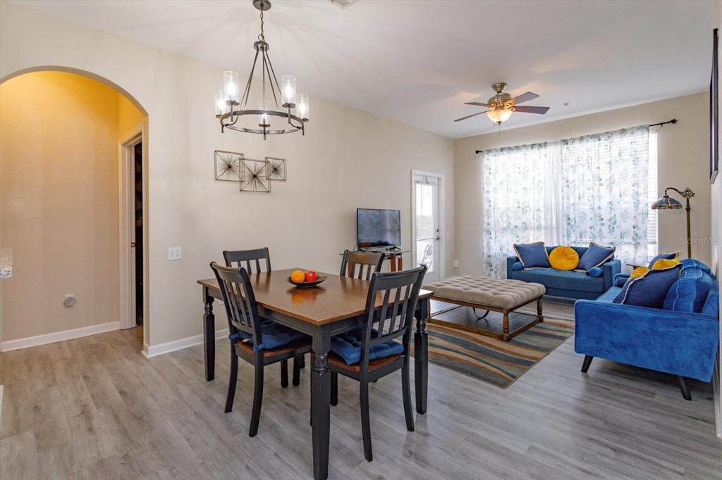 A dining area with a wooden table and chairs sits adjacent to a blue living room — 2310 SILVER PALM DR UNIT 104, KISSIMMEE, FL
